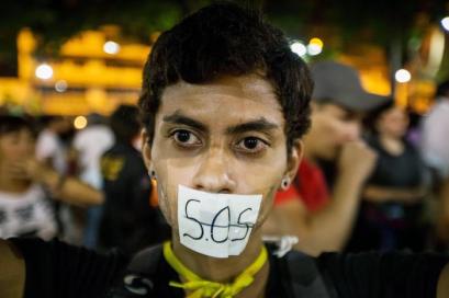 epaselect epa05936379 A woman covers her mouth with a sign reading 'S.O.S.' (the international Morse code distress signal) during vigil in Caracas, Venezuela, 29 April 2017. Venezuelan students held a 12-hour vigil in honor of people whom lost their lives during the recent anti-government rallies, while opposition parties called for another march on Monday in order to call for general elections and a new Supreme Court. EPA/MIGUEL GUTIERREZ